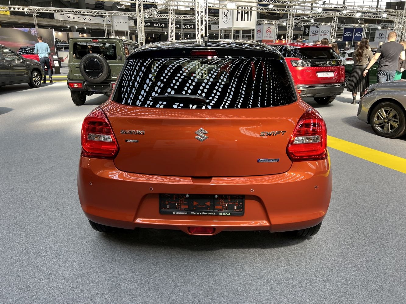 Rear view of orange hatchback with hybrid badge and distinctive taillights