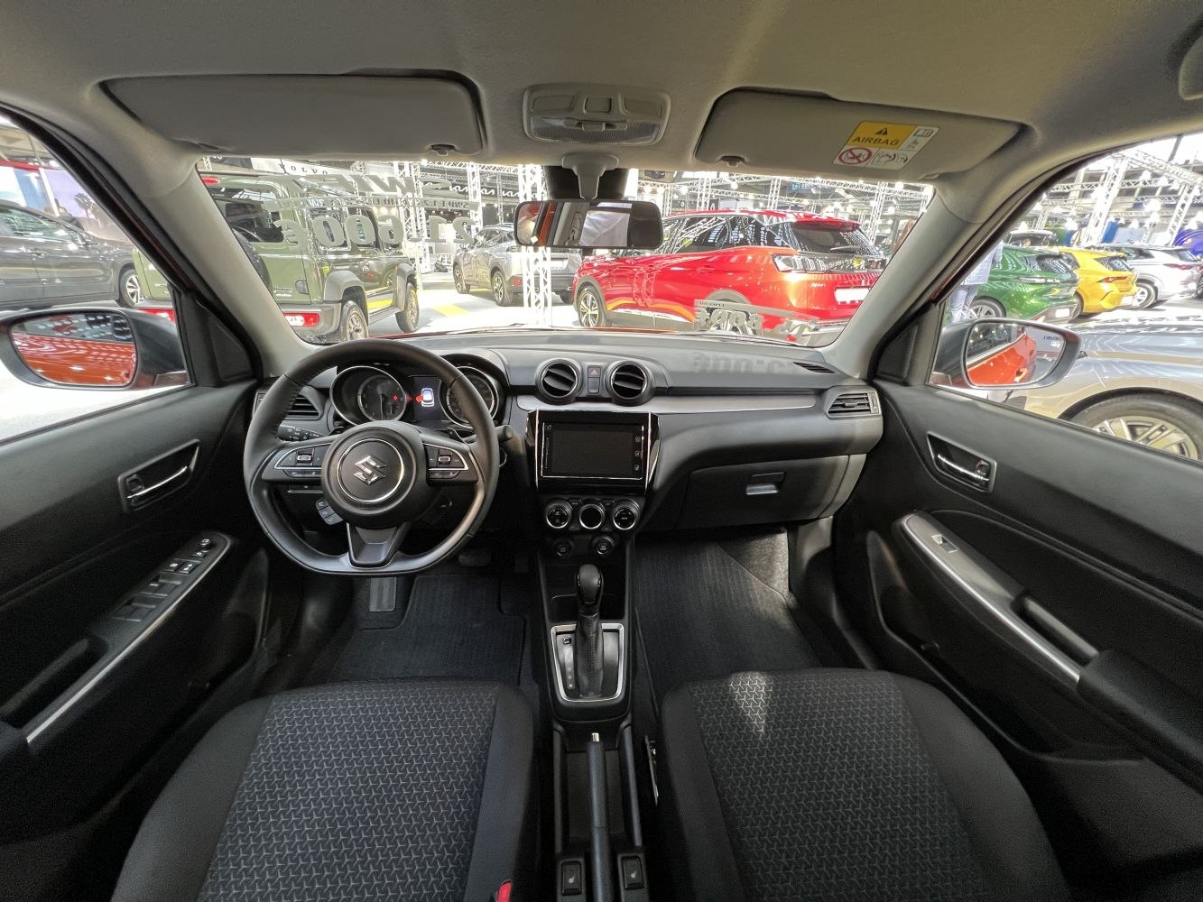 Dashboard and steering wheel with controls, central touchscreen, compact car interior.
