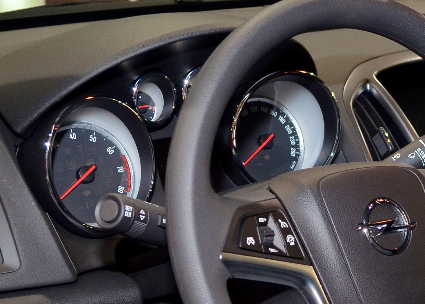 Close-up of car speedometer, instrument cluster, and steering wheel controls.