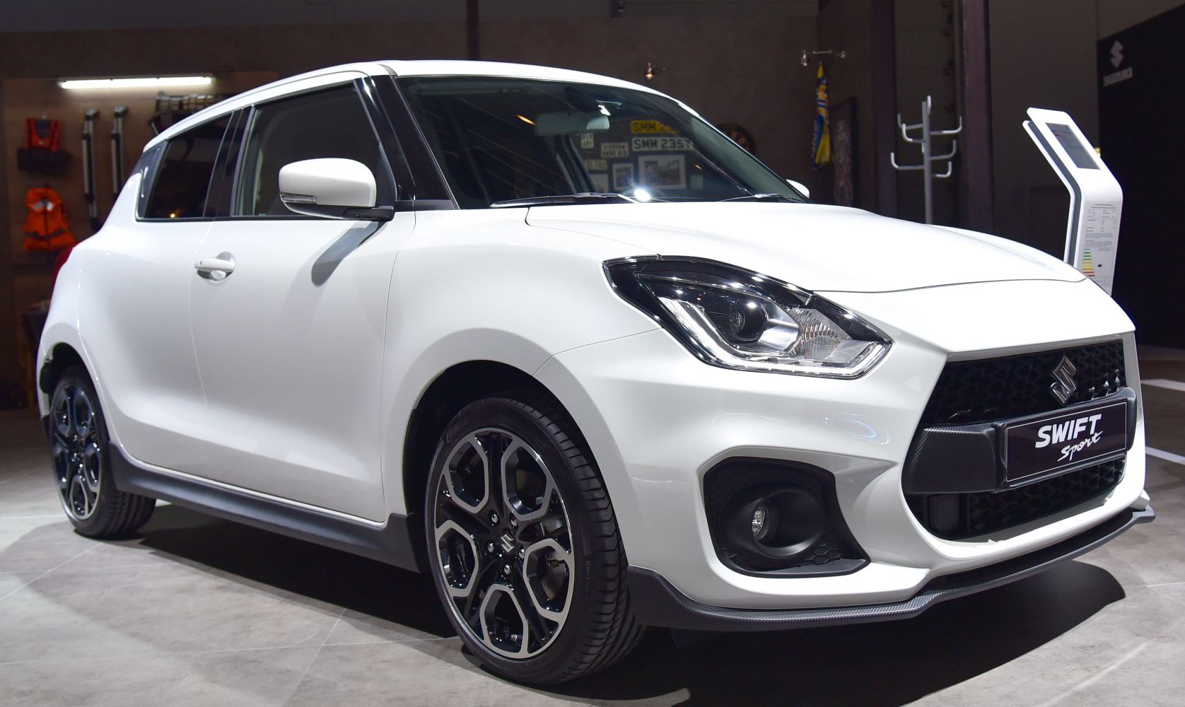 White hatchback front three-quarter view with headlights and alloy wheels