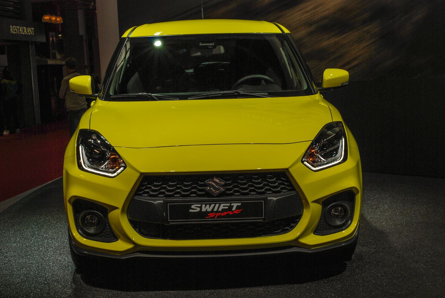 Yellow hatchback with aggressive headlights and honeycomb grille
