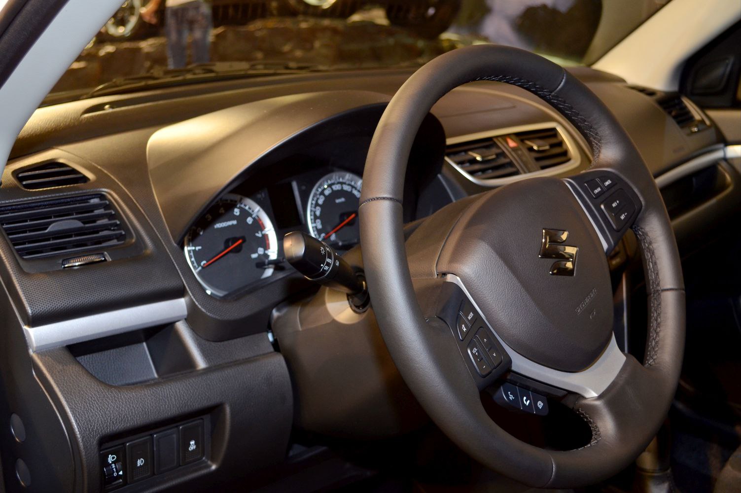 Steering wheel with control buttons and instrument cluster in car interior.