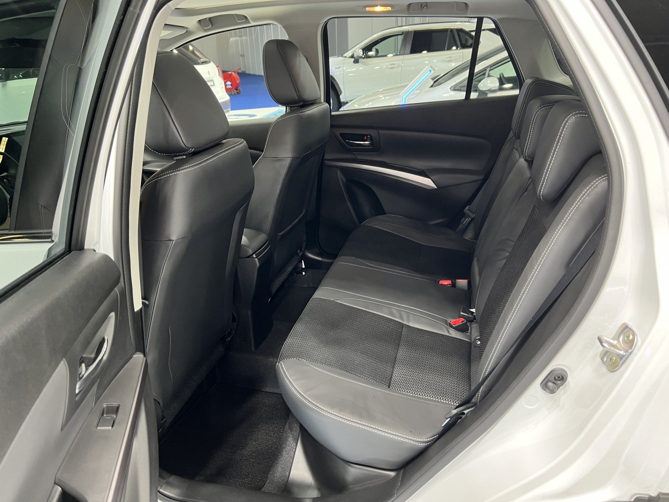 Spacious rear seats with black leather upholstery and white stitching