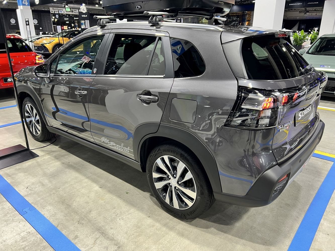 Rear side view of a grey SUV with roof rails and roof box