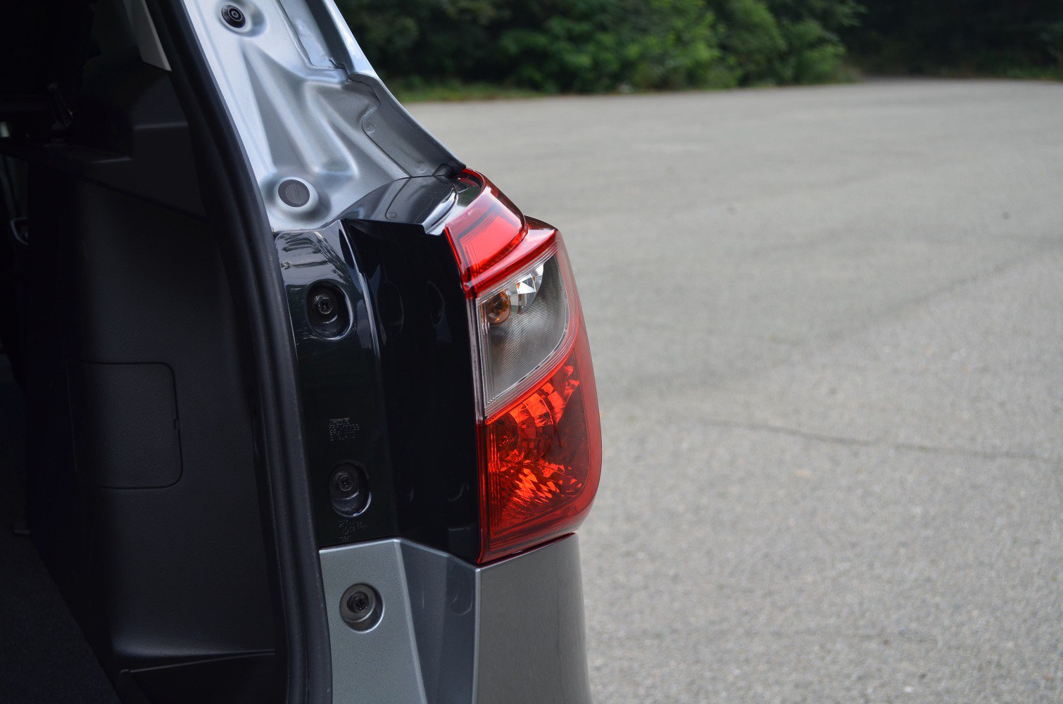 Close-up of a vehicle's rear tail light and open trunk area.