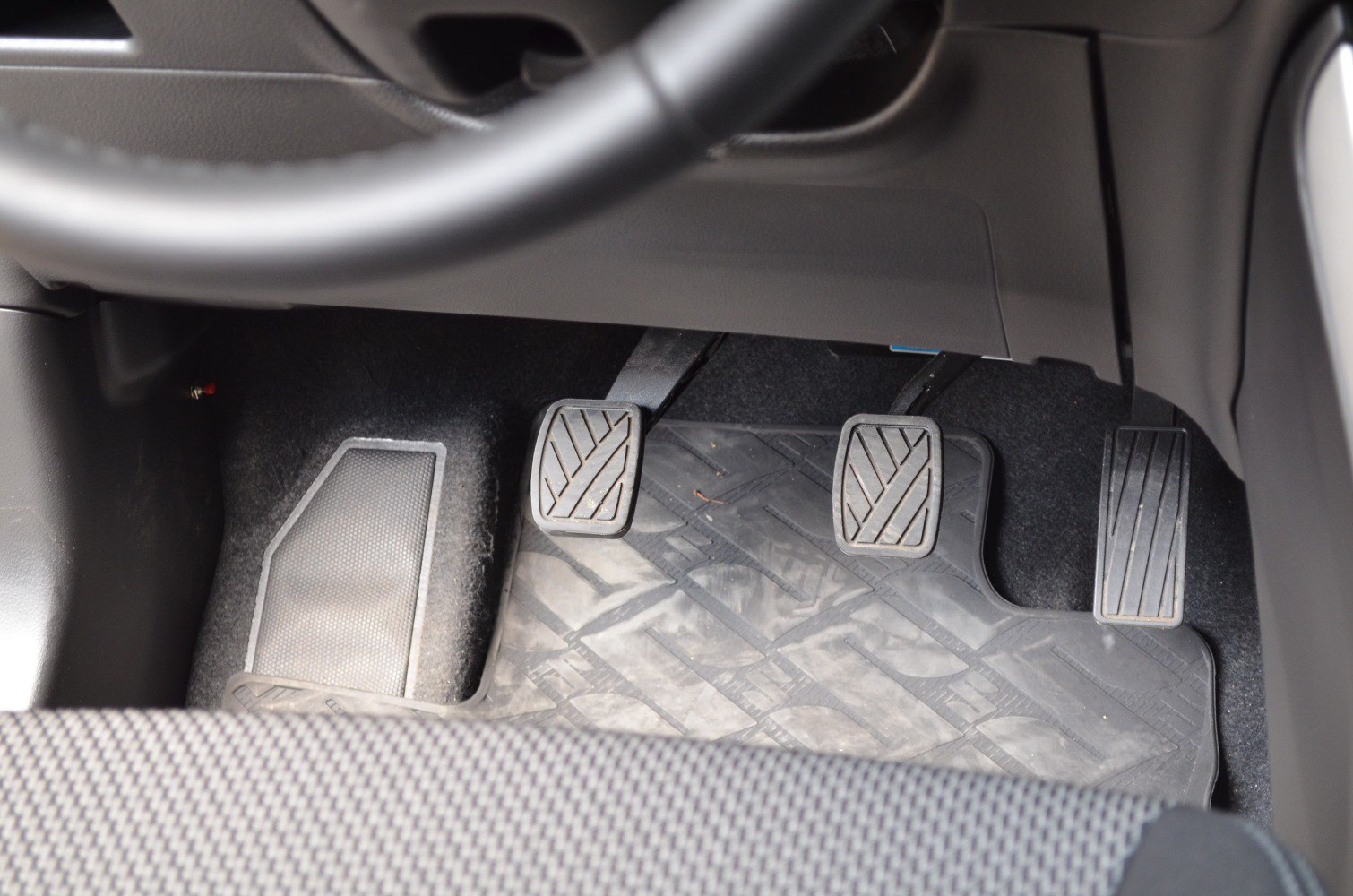 Manual transmission pedals with clutch, brake, and accelerator in car interior