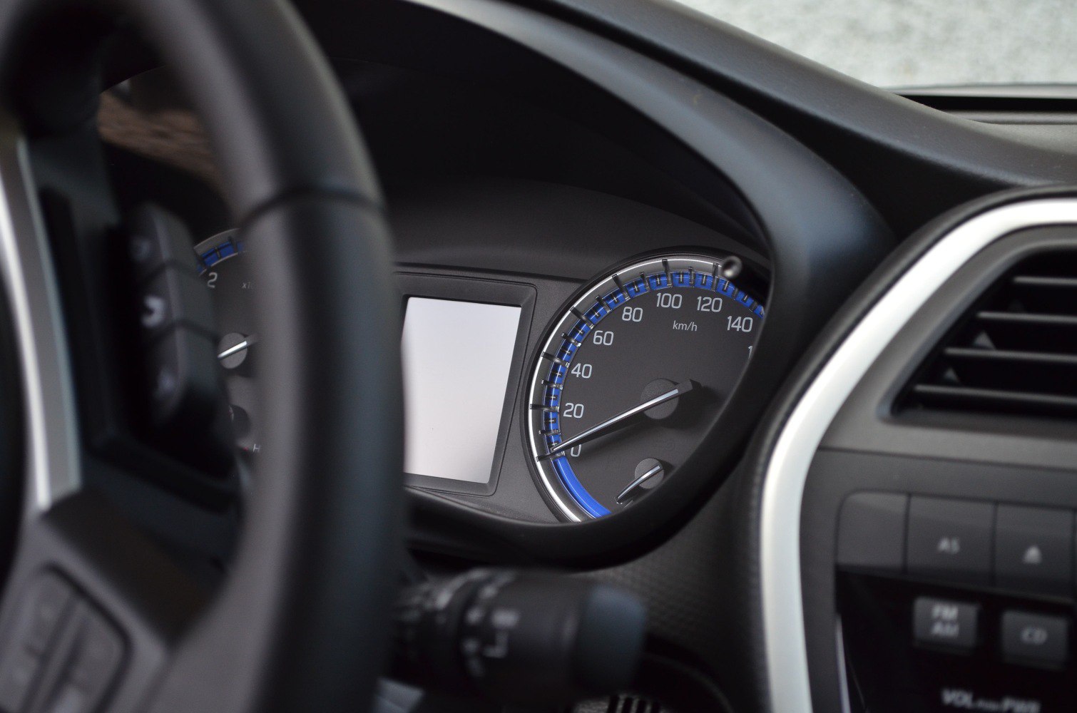Close-up of instrument cluster and speedometer with blue accents and blank display screen.