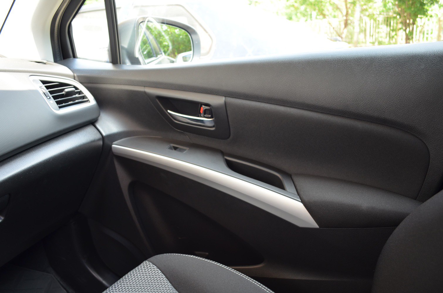 Interior passenger side door panel with handle, window control, and textured design