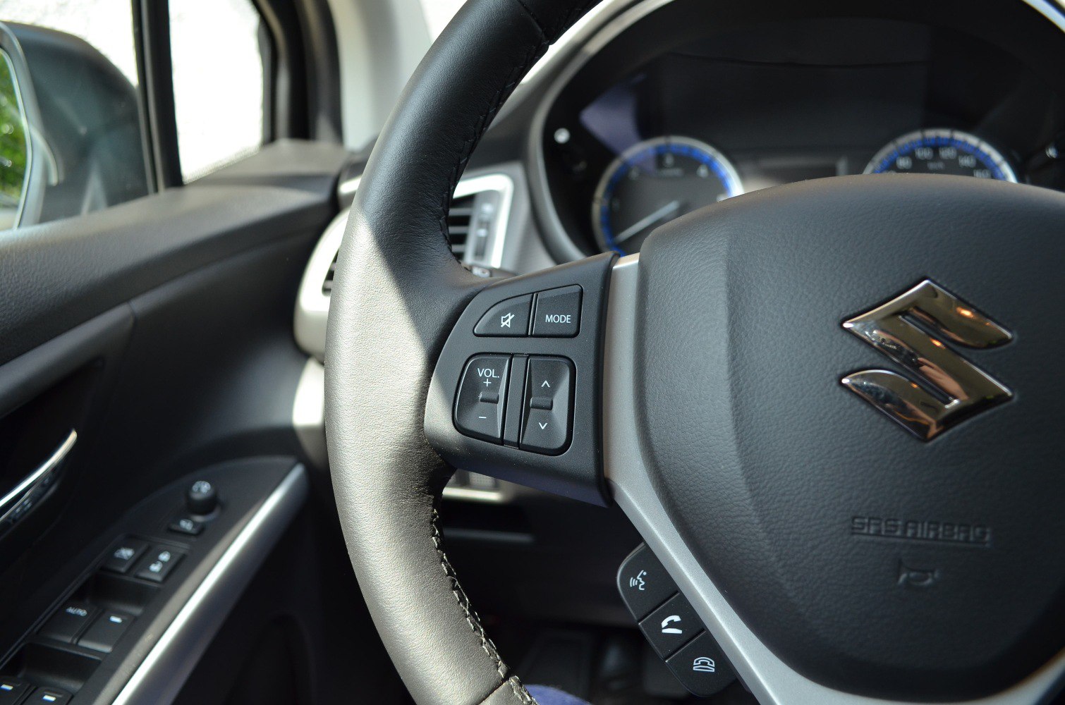 Close-up of steering wheel controls and interior door panel buttons