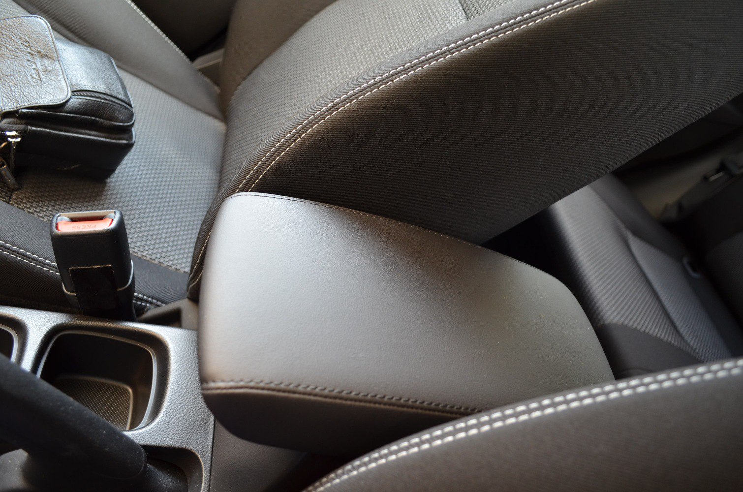 Center armrest and seatbelt buckle of fabric car seats with detailed stitching