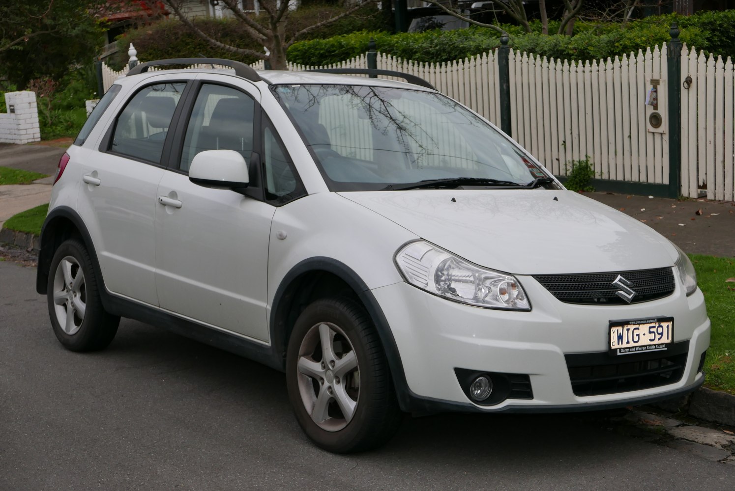 Compact white crossover with roof rails and distinctive headlights