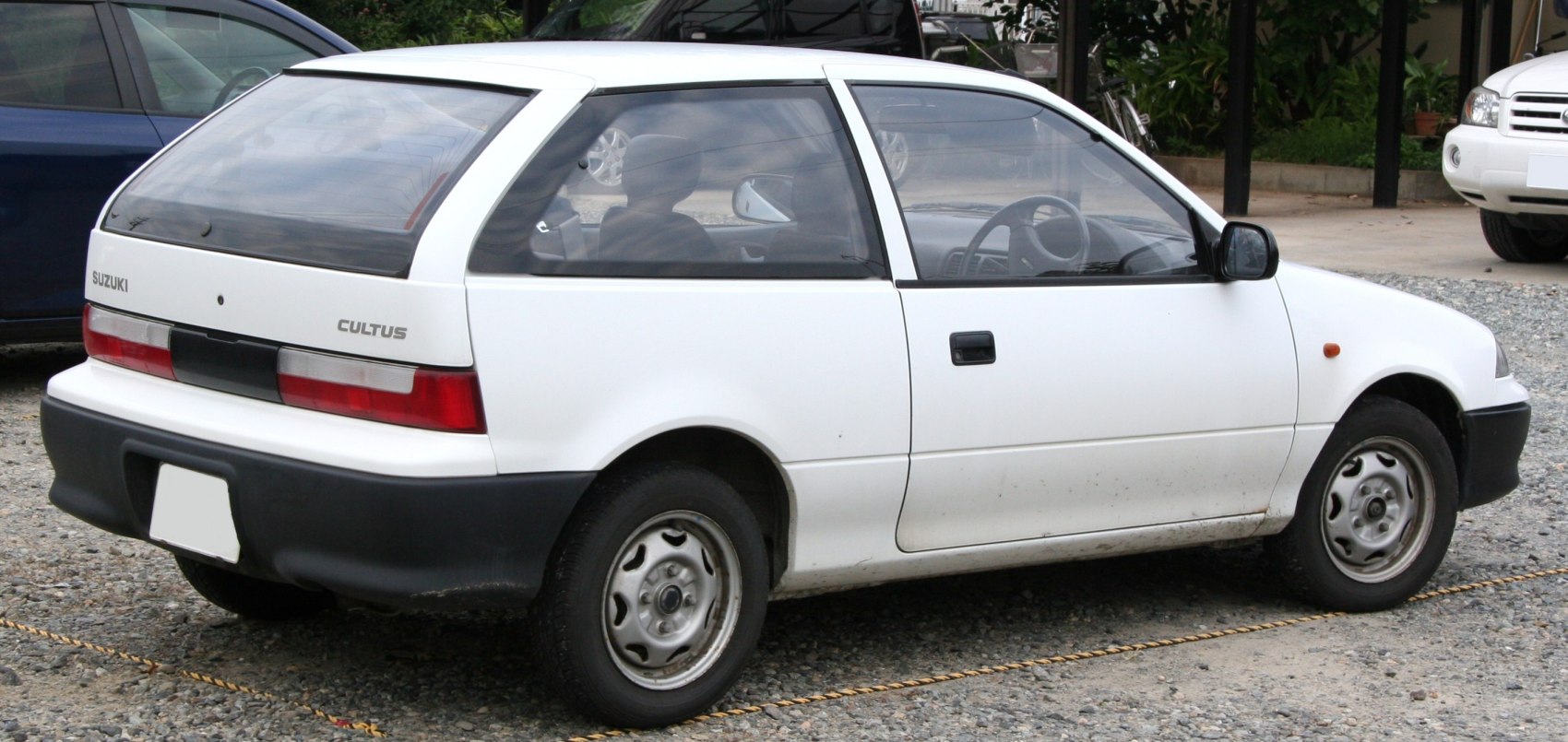 Compact white hatchback showing rear side with black bumper and rear window