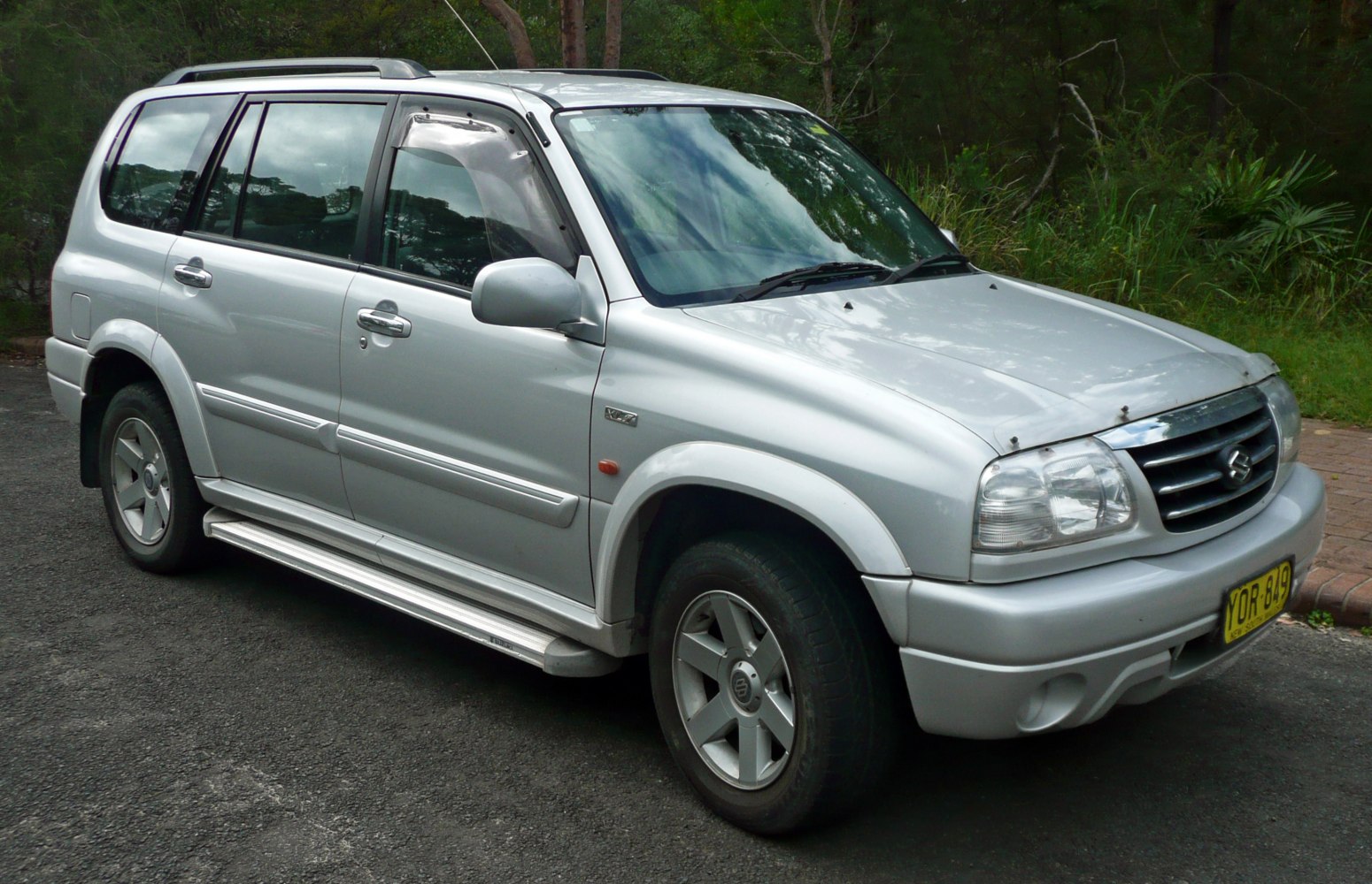 Silver SUV with alloy wheels and side steps, front-side view