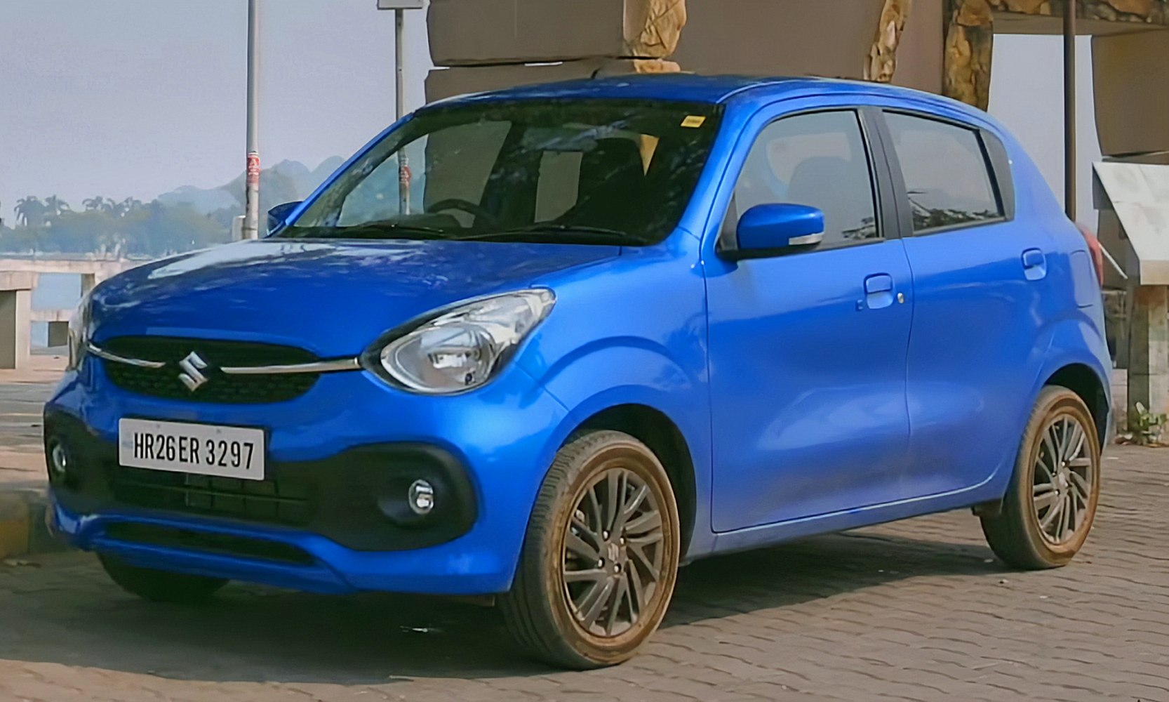 Blue hatchback front side with grille, headlight, and alloy wheels