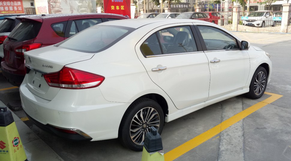 Rear-side profile of a white sedan with alloy wheels