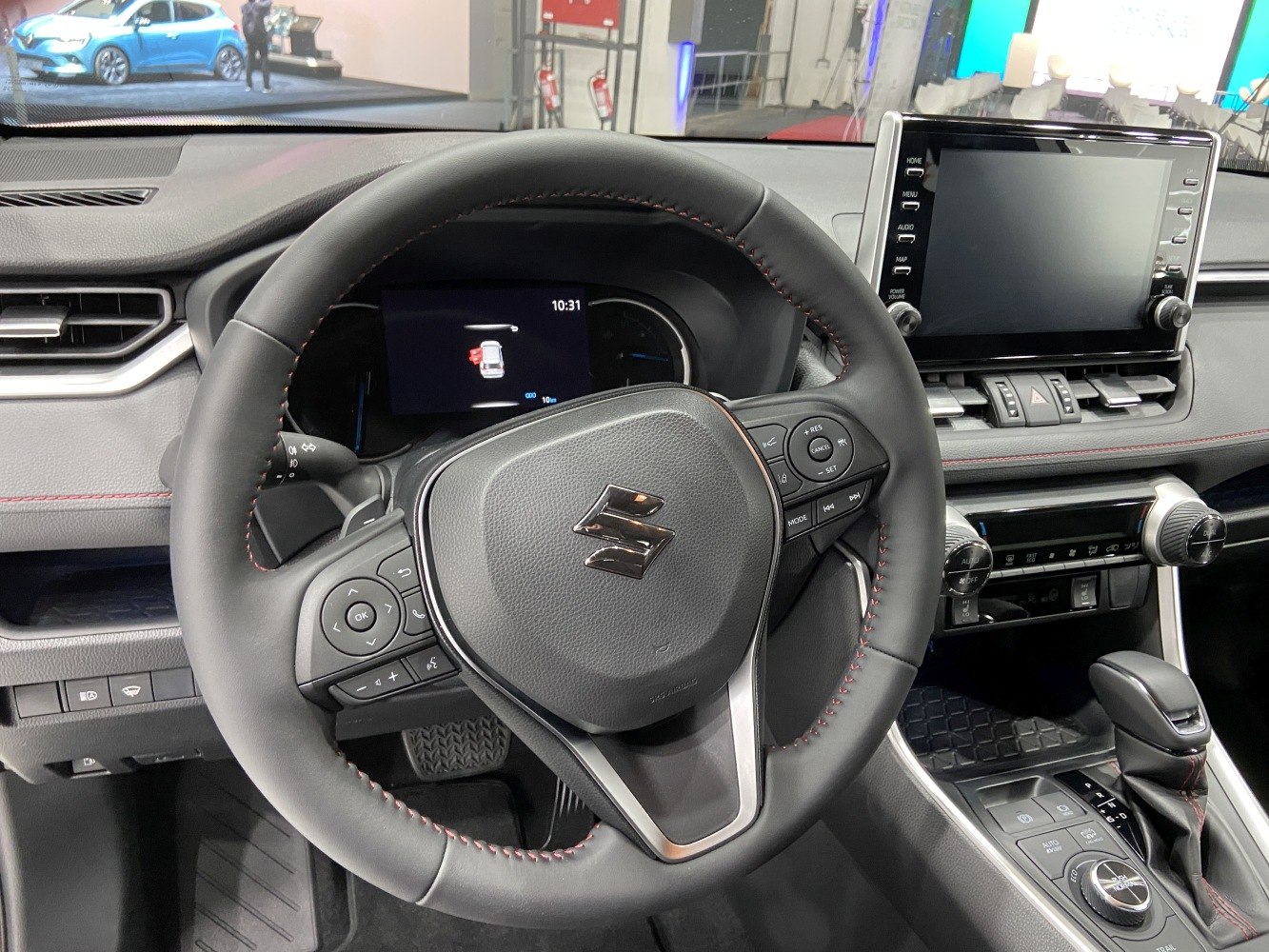 Steering wheel with controls, digital instrument display, infotainment screen, and gear shifter.