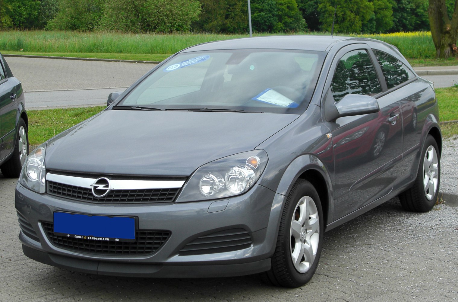 Front side view of a gray hatchback with headlights and alloy wheels