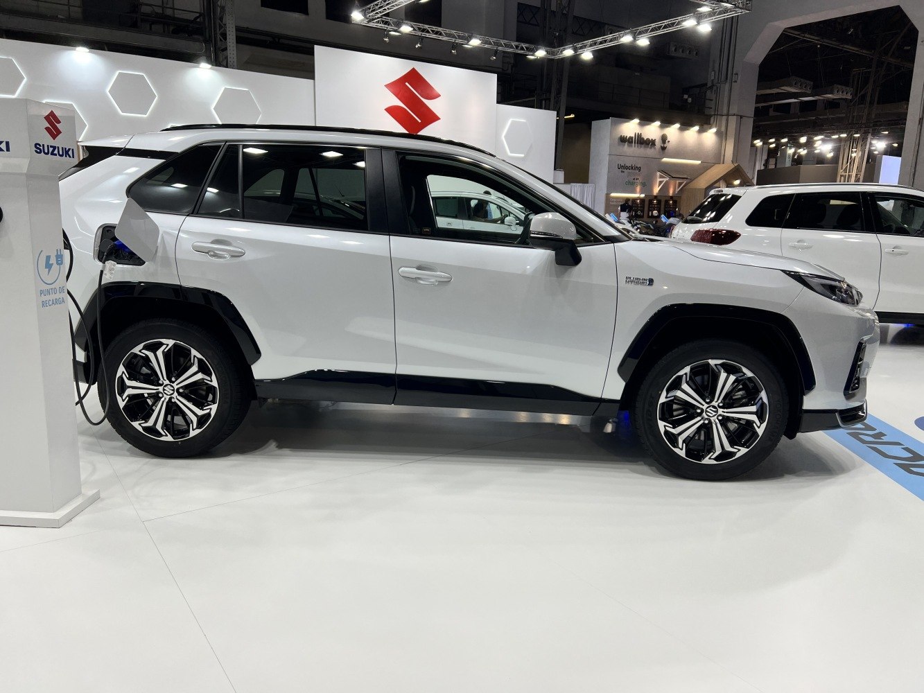 Side profile of white electric SUV plugged into charging station