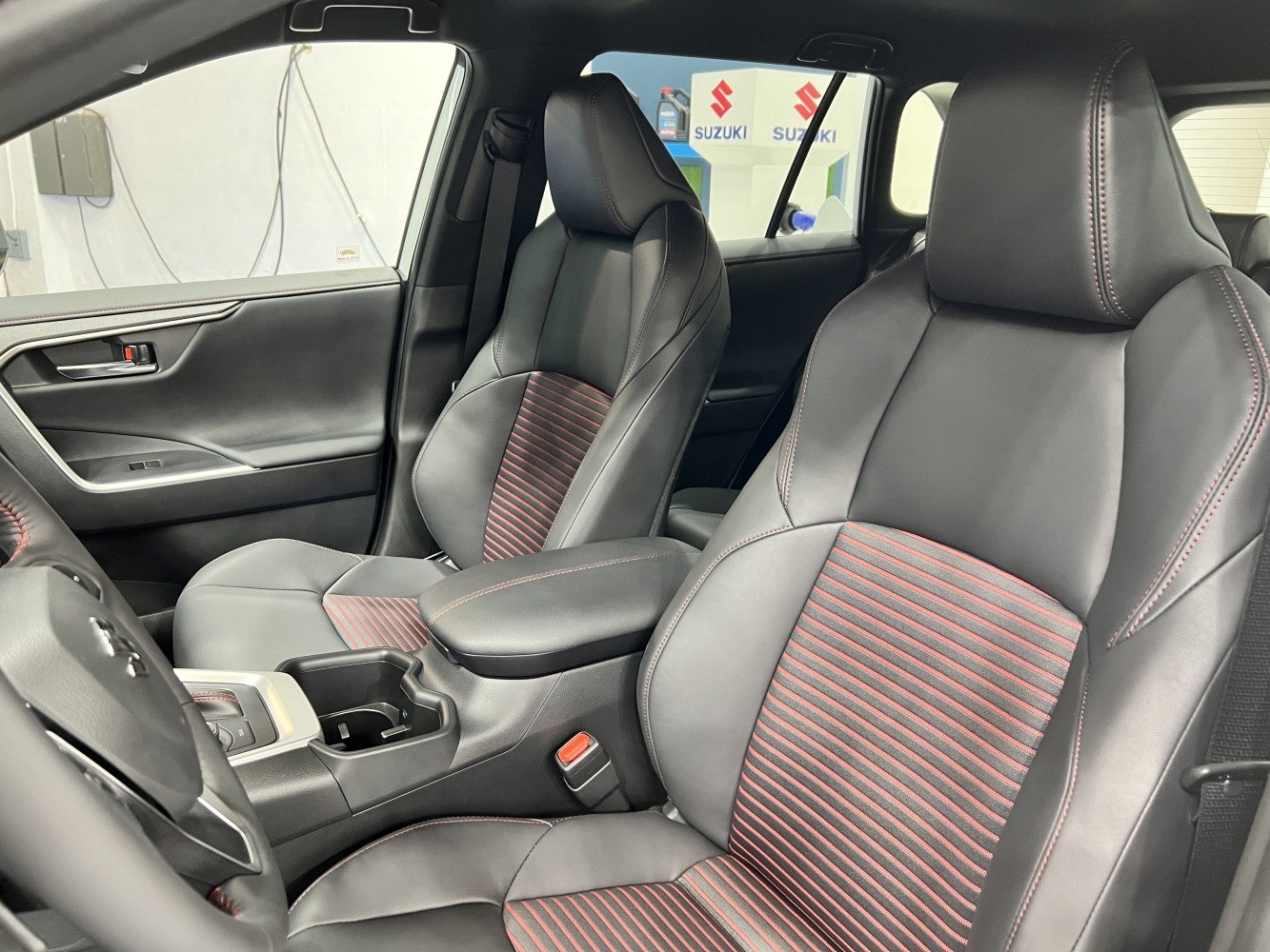 Black leather front seats with red horizontal trim and armrest.