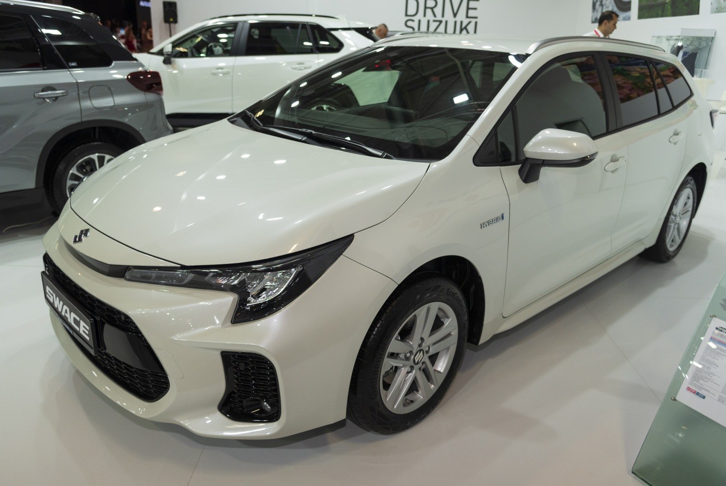 White hybrid vehicle with sleek headlights and sporty grille