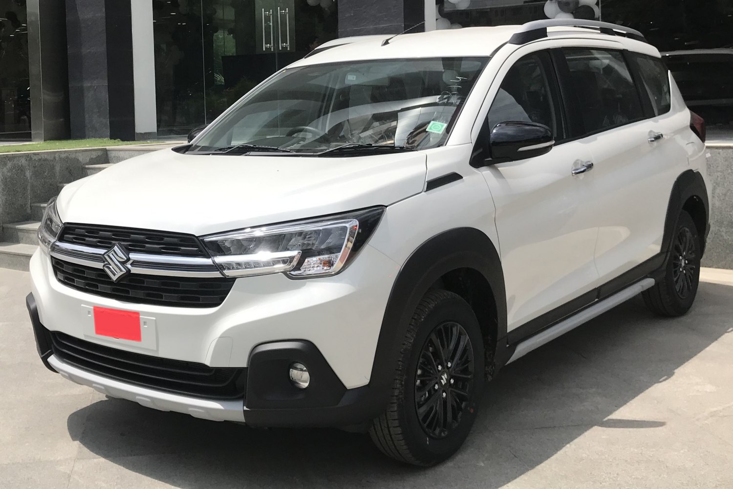 Front side view of a white SUV with black alloy wheels and roof rails