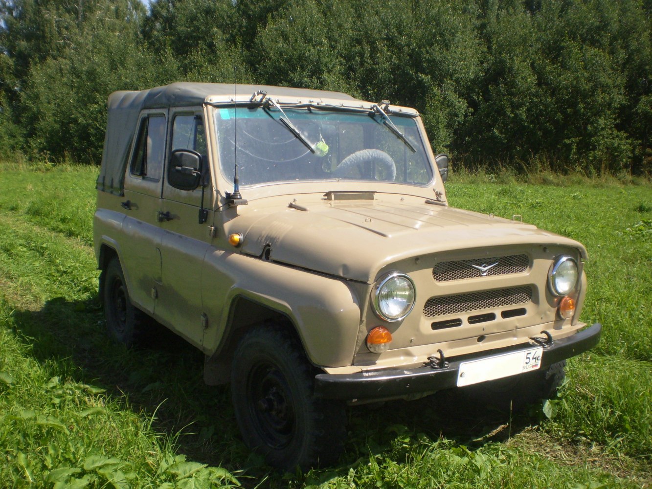 Boxy 4x4 utility vehicle with beige soft top and round headlights