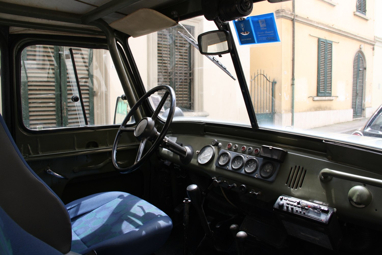 Vintage dashboard with speedometer, manual controls, and blue driver seat