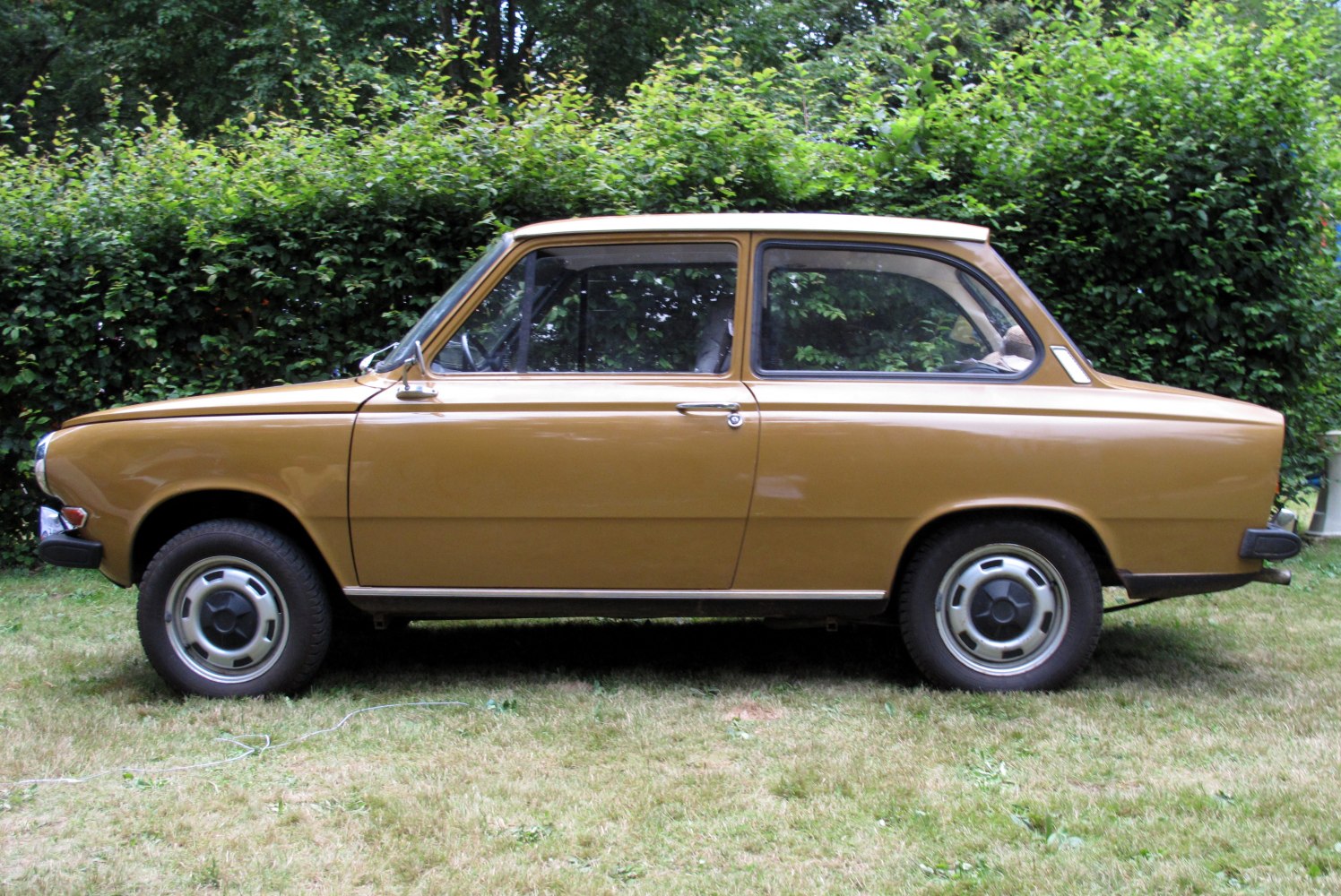 Classic vintage sedan side profile with chrome steel wheels and simple 1970s design.