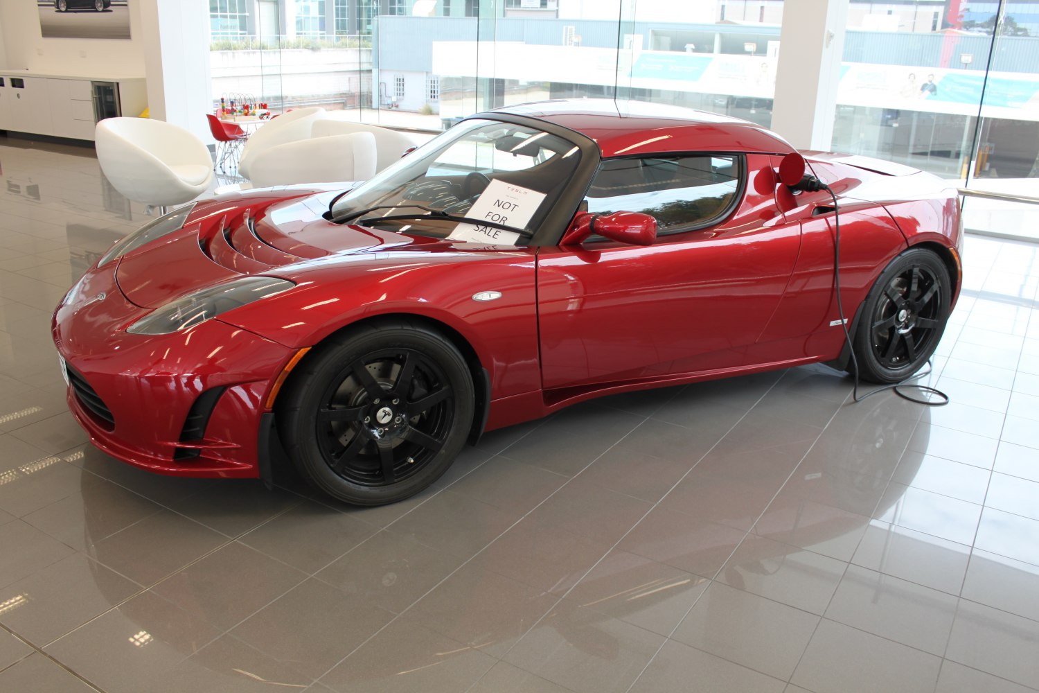 Red electric sports coupe with black wheels charging indoors