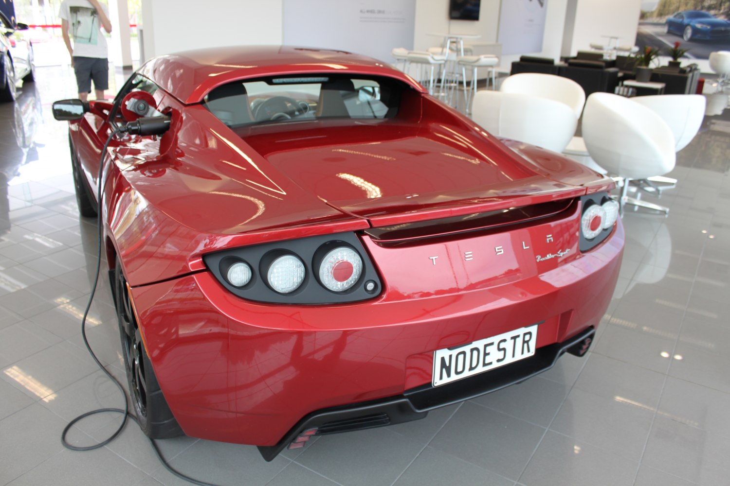 Rear view of a red electric sports car with charging cable and unique taillights