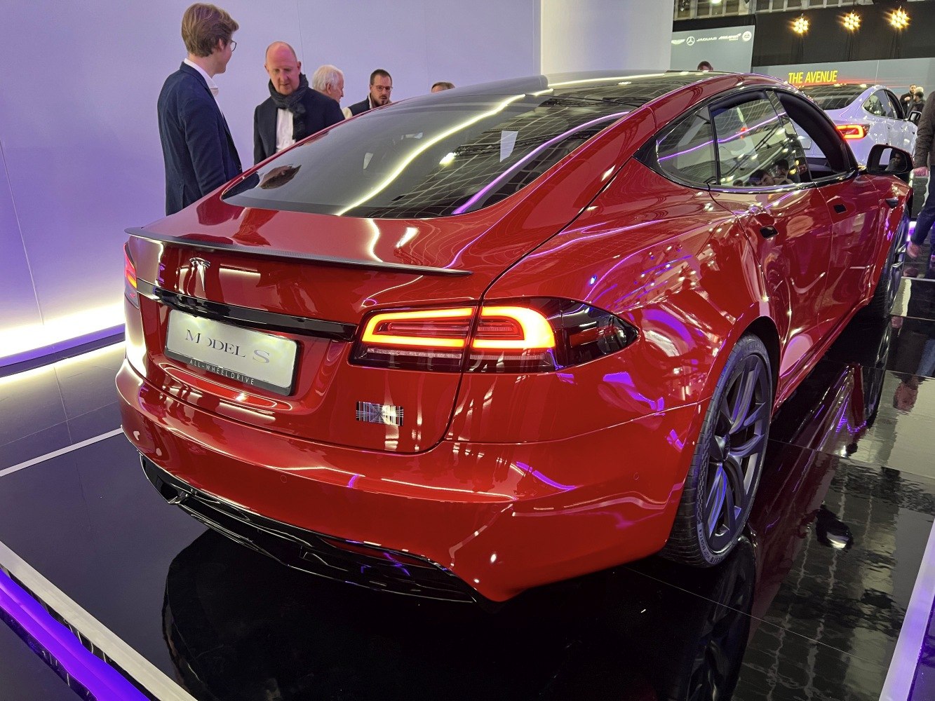 Red electric sedan rear with LED tail lights and spoiler