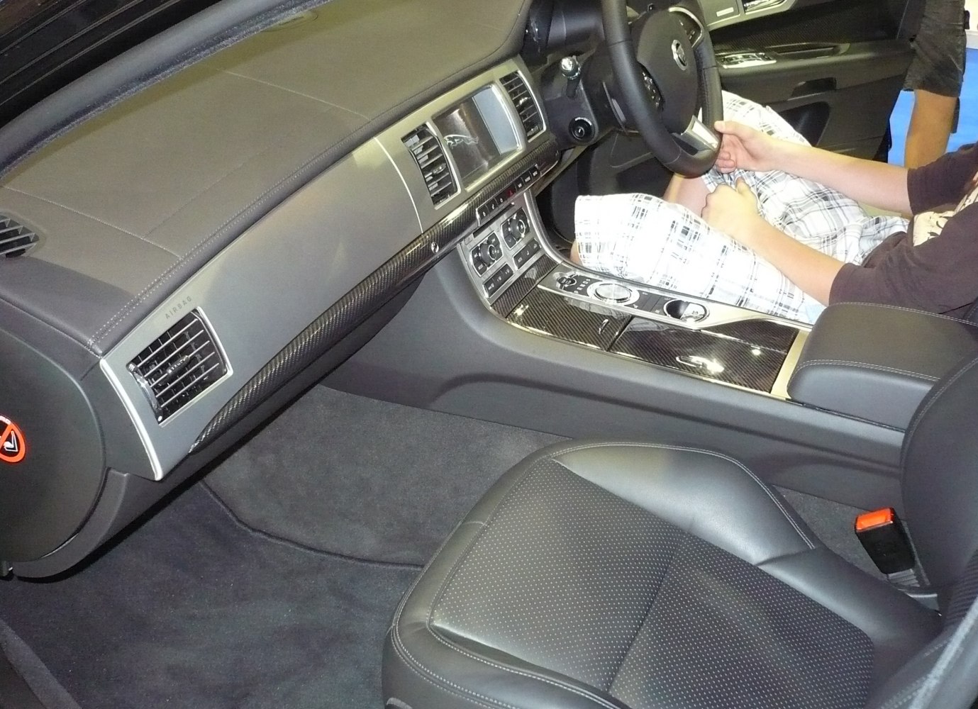 Luxury car interior with dashboard and center console featuring leather and carbon fiber trim