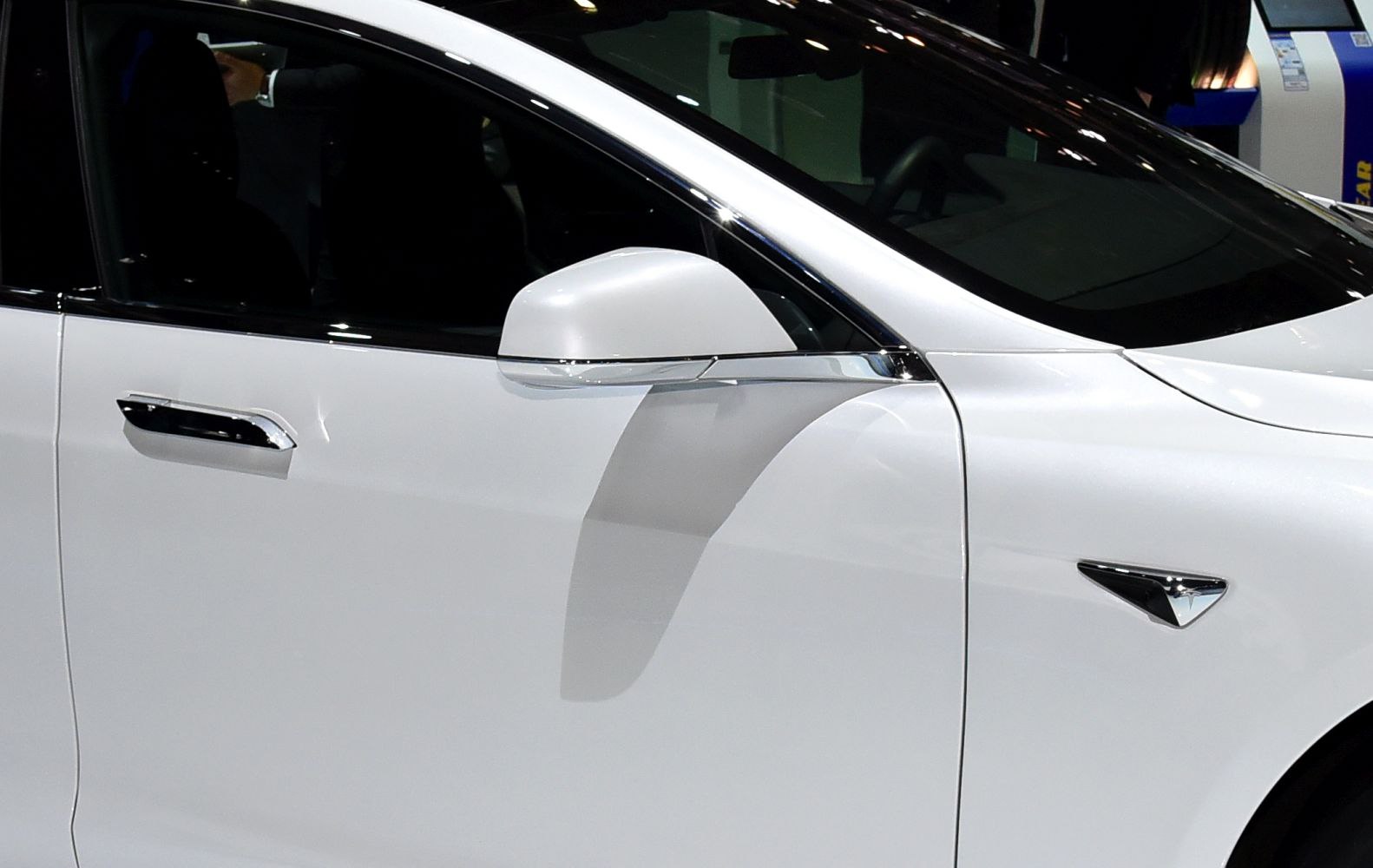 Close-up of white door mirror and door handle with side panel.