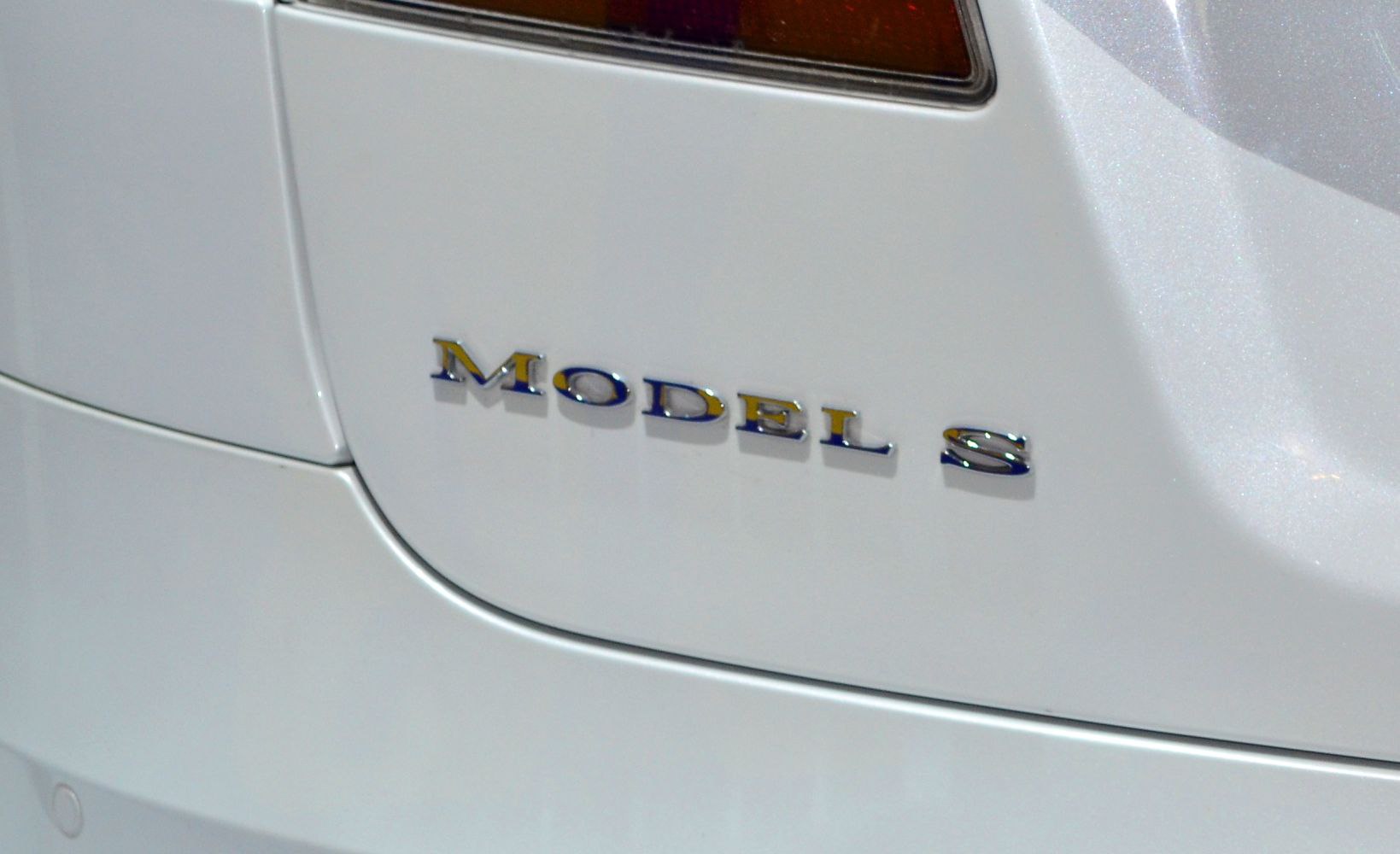 Close-up of rear badge 'Model S' on a white car surface