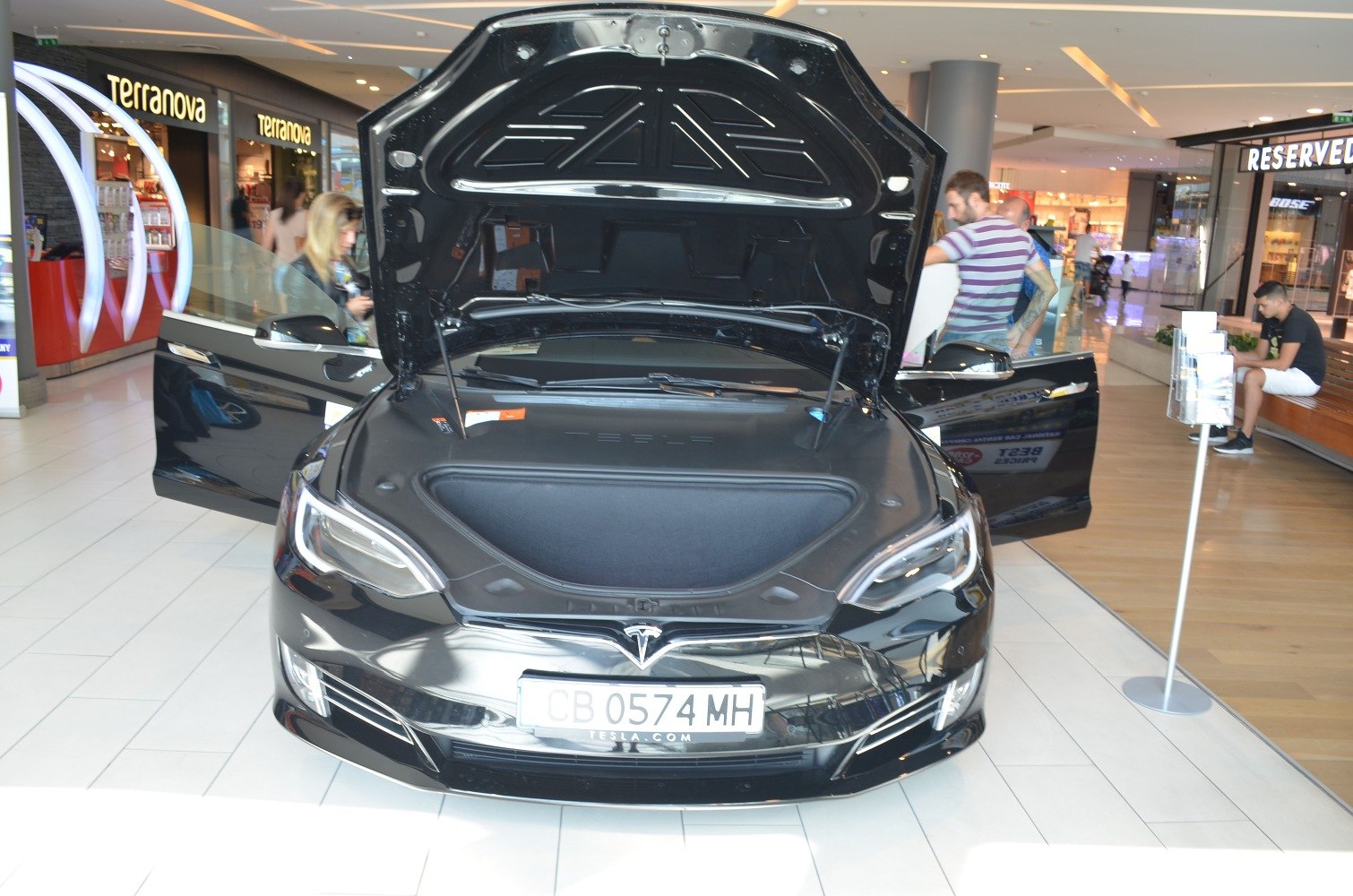 Front trunk (frunk) and open front doors of a black electric luxury sedan
