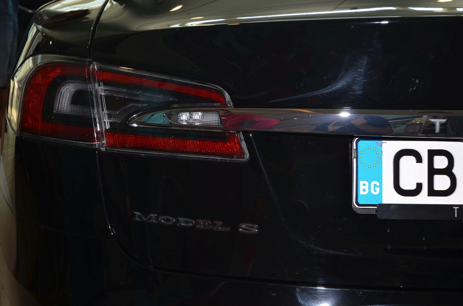 Close-up of rear tail light and Model S badge on black Tesla