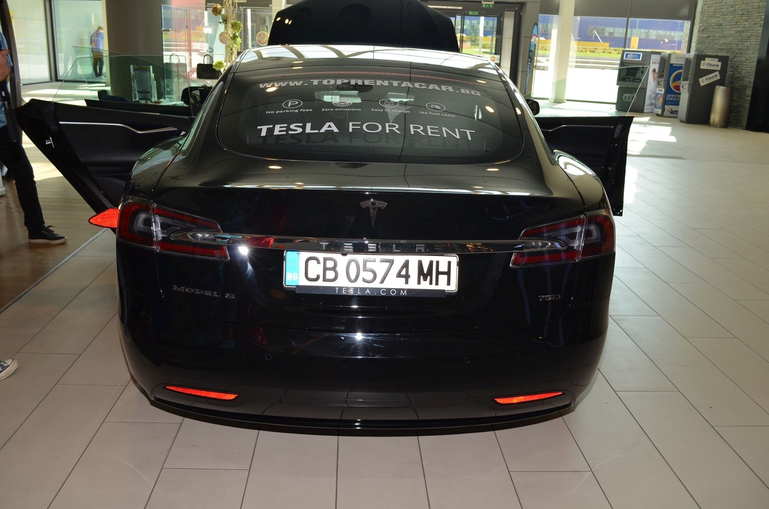 Rear view of Tesla Model S facelift with open rear doors and visible taillights