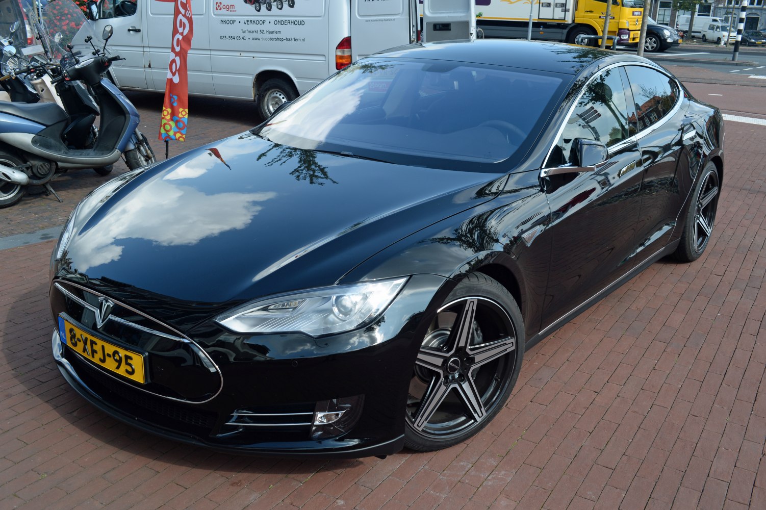 Aerodynamic black sedan with sharp headlights and five-spoke alloy wheels