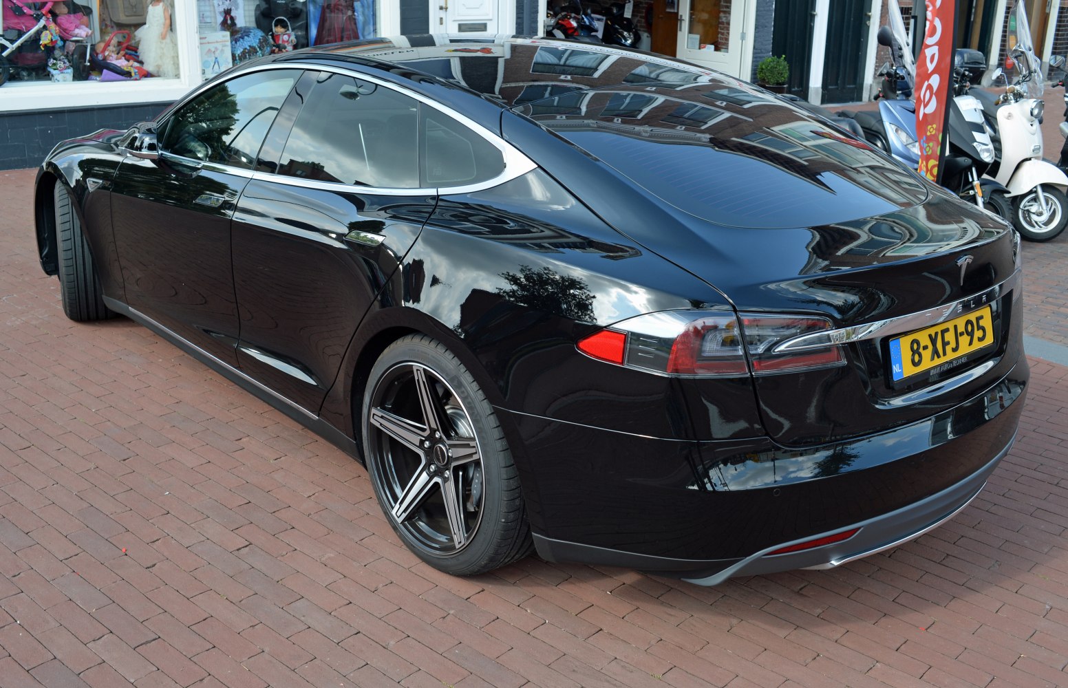 Rear and side view of a sleek black electric sedan with distinct taillights