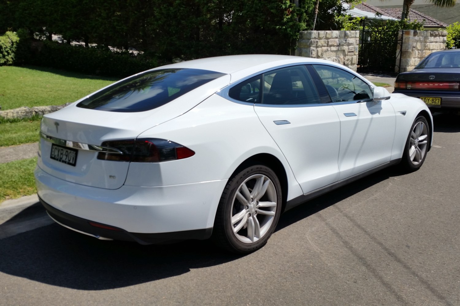 Rear and side view of a white electric luxury sedan with sleek, aerodynamic design.