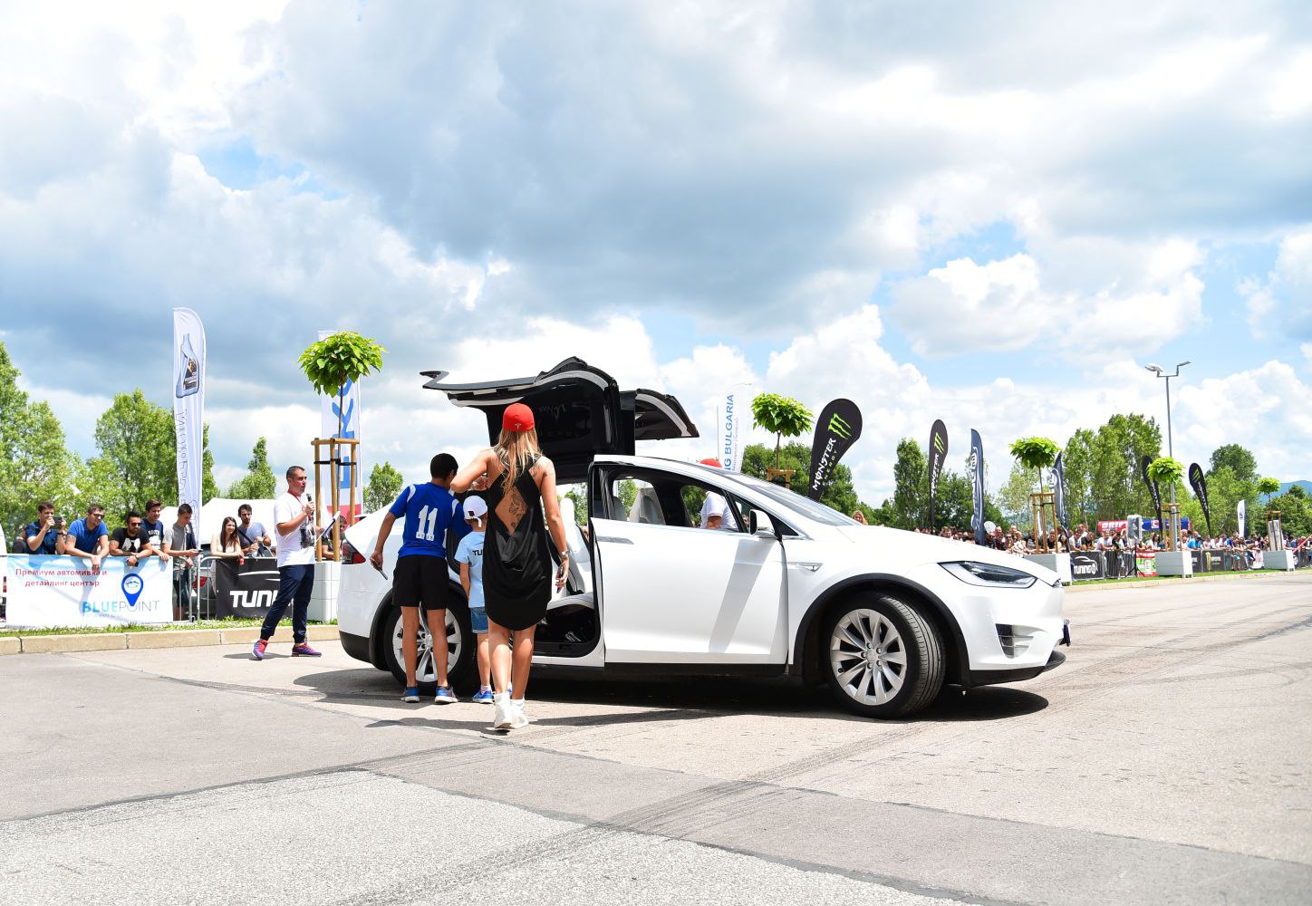 White electric SUV with falcon wing doors open.