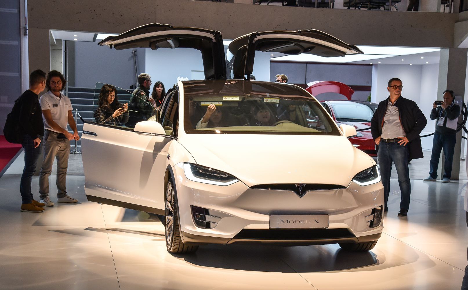 White electric SUV with open falcon wing doors and LED headlights.