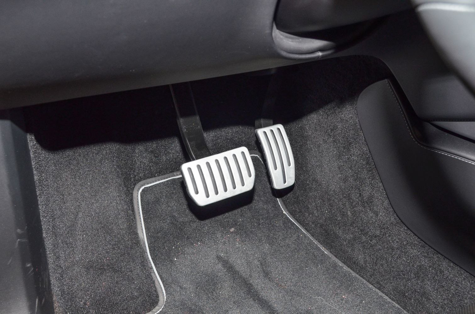 Brake and accelerator pedals with floor mat in car interior