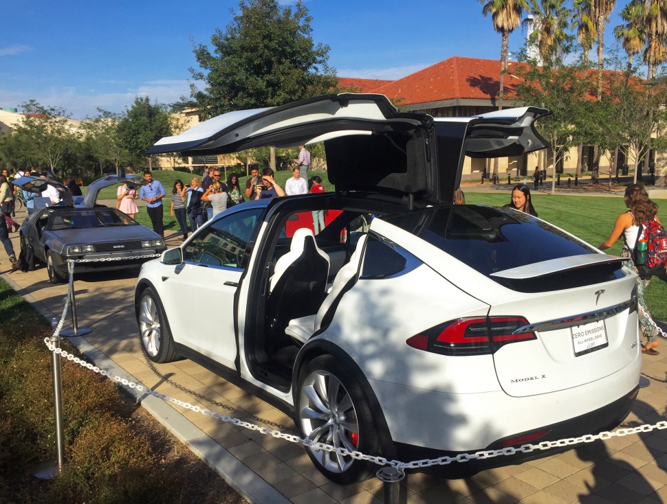 White Tesla SUV with distinctive gull-wing falcon doors open on both sides.