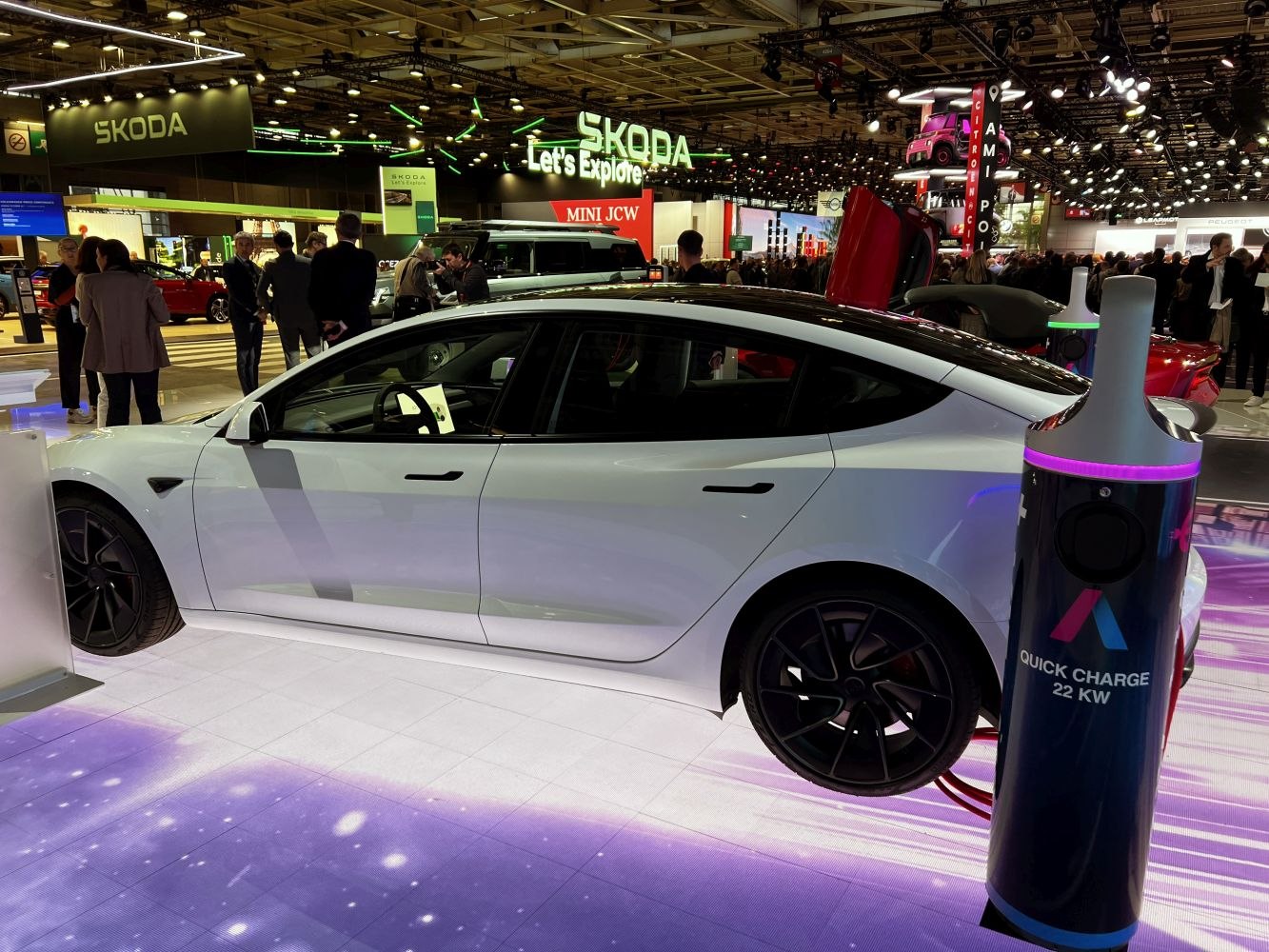 Side profile of white electric sedan with quick charge station