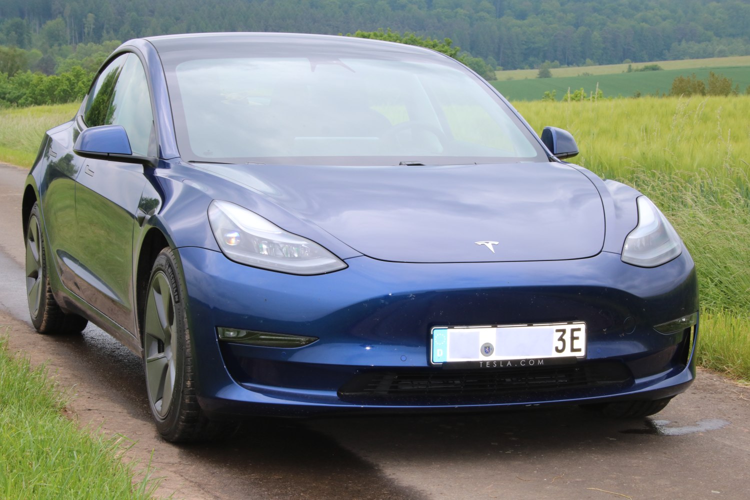 Blue electric sedan with sharp headlights and aerodynamic front.