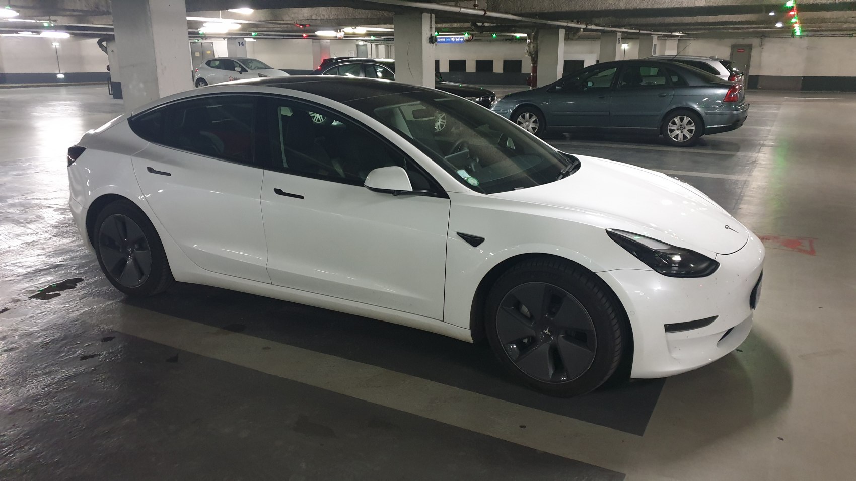 White electric sedan with aerodynamic wheels in underground parking