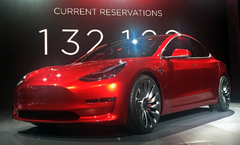 Red electric sedan with aerodynamic wheels and sleek modern headlights