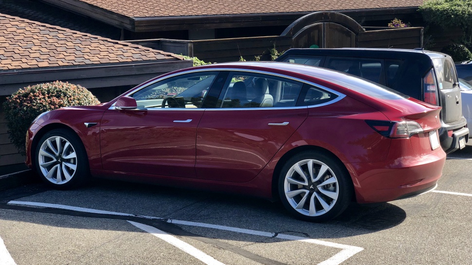 Side profile of red electric sedan with aerodynamic curves and distinctive alloy wheels