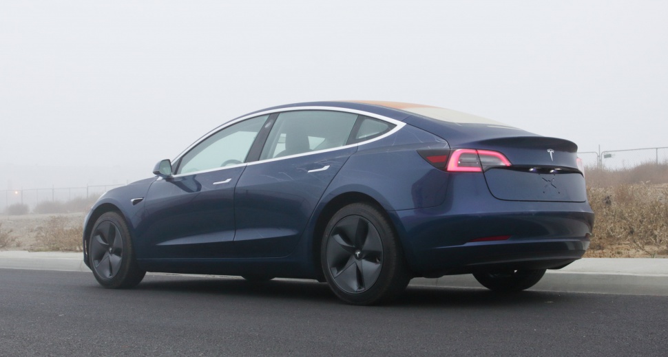 Rear side view of an aerodynamic electric sedan with distinctive taillights and dark wheels.
